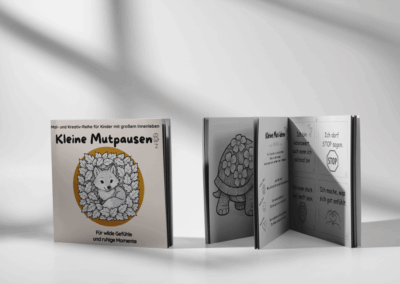 Aufgestelltes Exemplar des Kinderbuchs „Kleine Mutpausen – Für wilde Gefühle und ruhige Momente“ mit Fuchs-Cover, daneben geöffnete Bücher, die eine Schildkröte, kreative Ideen und Affirmationen zum Ausmalen zeigen.